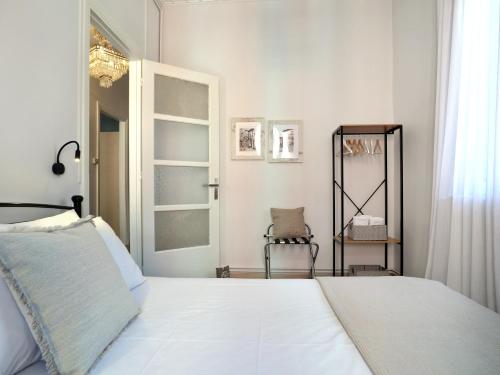 a bedroom with a white bed and a chair at La Casa Buranella in Lefkada