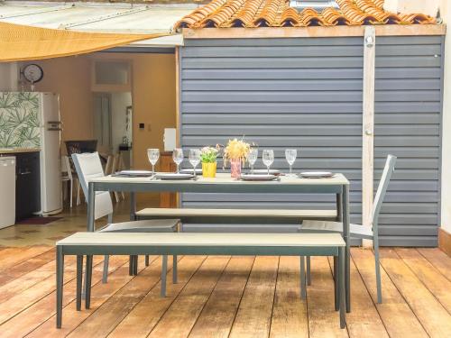 - une table avec des chaises et des verres à vin sur la terrasse dans l'établissement Agreable maison de vacances - quartier arago - 6 personnes, à Les Sables-dʼOlonne