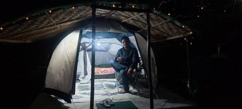 a man sitting in a tent with a wheelchair at Nisarg Camping Pods in Almora