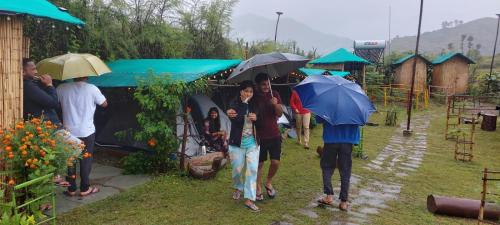 a group of people walking in the rain with umbrellas at Nisarg Camping Pods in Almora