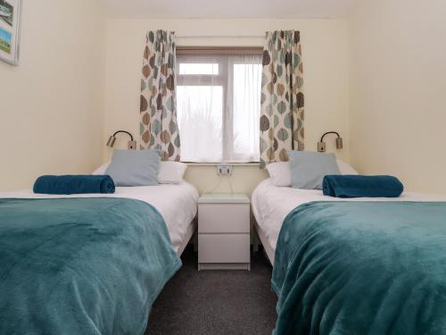 two twin beds in a room with a window at Kenegie Cottage in Penzance