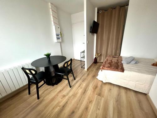 a bedroom with a bed and a table and chairs at Le Cosy Urbain 100 m Gare in Villefranche-sur-Saône