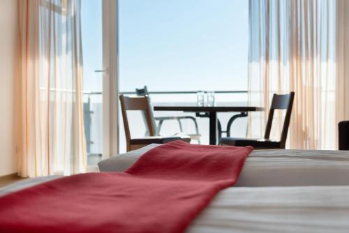a red blanket sitting on a bed in a room with a table at Gästehaus D i c k r e i t e r in Immenstaad am Bodensee