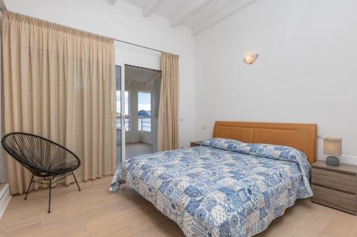 a bedroom with a bed and a chair and a window at Residenza Cormorani 2 in Golfo Aranci