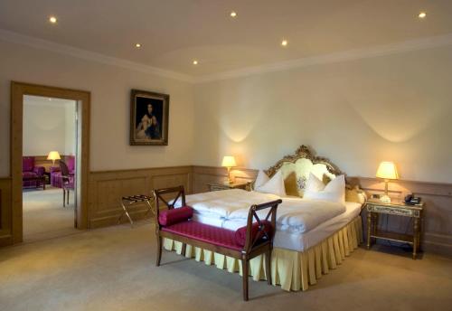 a bedroom with a king sized bed with a red seat at Schloss Diedersdorf in Diedersdorf