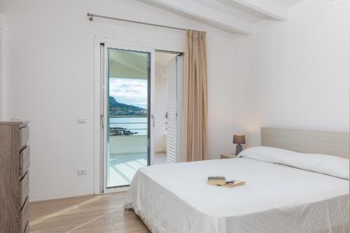 a white bedroom with a bed and a balcony at Villa Cormorani 1 in Golfo Aranci