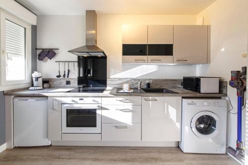 une cuisine avec des armoires blanches et une laveuse et une sécheuse dans l'établissement Létanduère Wifi Tramway, à Angers