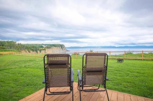 two chairs sitting on a deck with a view of the ocean at Chalets Nautika in Gaspé