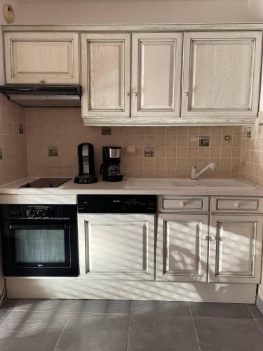 une cuisine avec des armoires blanches et un appareil noir dans l'établissement Appartement 6 personnes Héliopolis - K 204, au Cap d'Agde