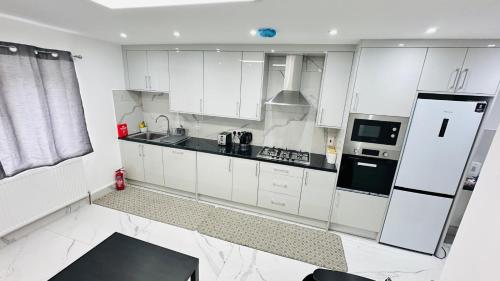 a kitchen with white cabinets and a black and white appliances at 93 New Road in Harmondsworth