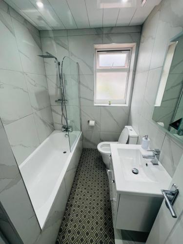 a bathroom with a tub and a toilet and a sink at 93 New Road in Harmondsworth