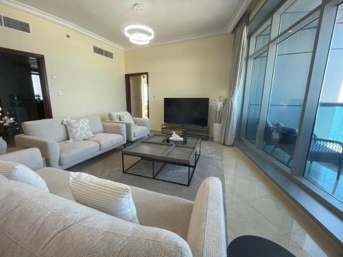 a living room with couches and a flat screen tv at Beachfront gem, waves and sunset in Ajman 