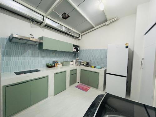 een keuken met groene kasten en een witte koelkast bij Sun sun house in Chiang Mai