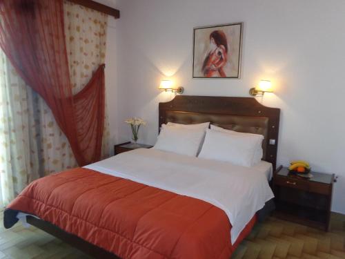 a bedroom with a large bed with a red and white blanket at Angela Hotel in Agia Marina Aegina
