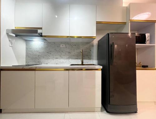 a kitchen with a black refrigerator and white cabinets at Modern Makati Condo with Balcony & Cityscape Views in Manila