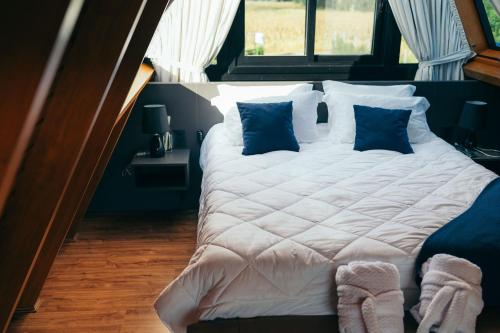 a large white bed with blue pillows in a room at Alpinada Cabanas in Carlos Barbosa