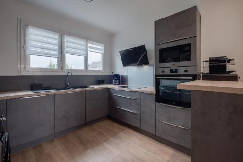 Il comprend une grande cuisine avec des appareils en acier inoxydable et du parquet. dans l'établissement Le Solférino Balcon Parking Wifi, à Laval