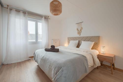 une chambre blanche avec un grand lit et une fenêtre dans l'établissement Le Solférino Balcon Parking Wifi, à Laval