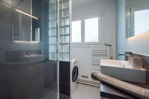 une salle de bain avec un lavabo et une machine à laver dans l'établissement Le Solférino Balcon Parking Wifi, à Laval
