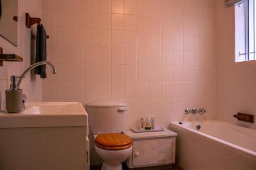 a bathroom with a toilet and a tub and a sink at The Mountainview Family Retreat in Hermanus