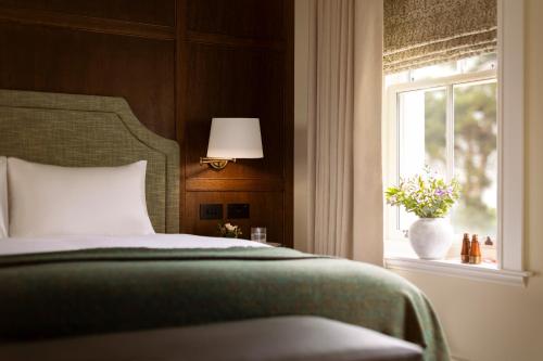 a bedroom with a bed and a window at Dunluce Lodge - Small Luxury Hotels of the World in Portrush