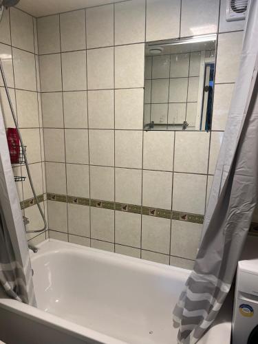 a bathroom with a bath tub and a mirror at Small house in Vilnius