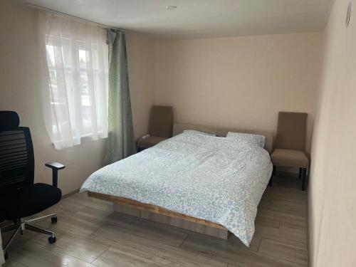 een slaapkamer met een bed, een stoel en een raam bij Small house in Vilnius