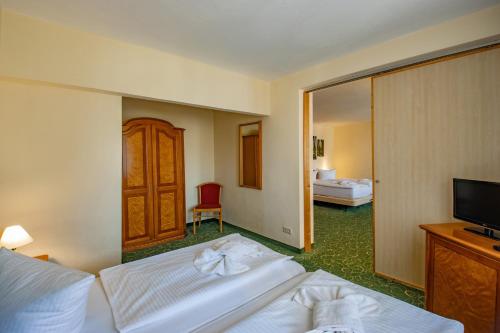 a hotel room with two beds and a television at Erzgebirgshotel Freiberger Höhe in Eppendorf