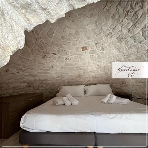 una cama en una habitación con una pared de piedra en Trullo Diaz Fanizza, en Alberobello