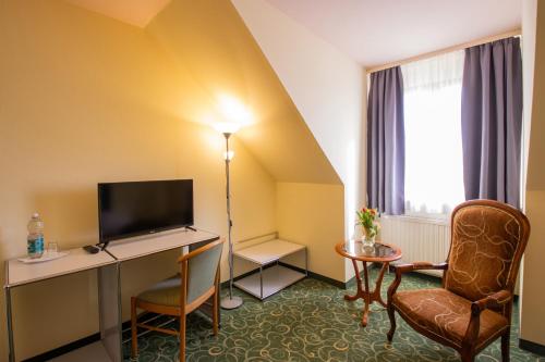 a hotel room with a television and a desk and a chair at Erzgebirgshotel Freiberger Höhe in Eppendorf