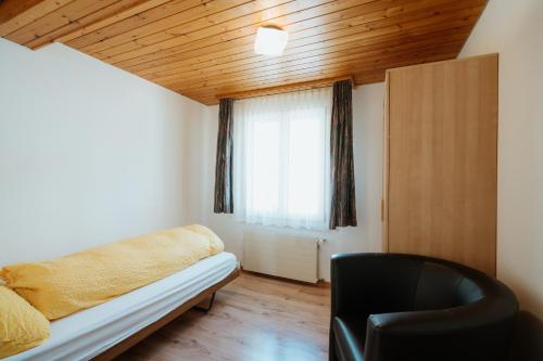 a bedroom with a bed and a chair and a window at Apartment Sonne in Amden