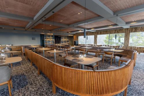 a dining room with tables and chairs and windows at Los Acebos Ushuaia Hotel in Ushuaia