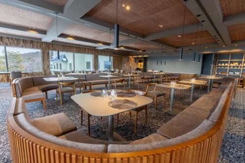 a restaurant with tables and chairs and windows at Los Acebos Ushuaia Hotel in Ushuaia