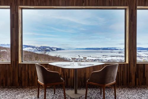 a room with a table and two chairs and a large window at Los Acebos Ushuaia Hotel in Ushuaia