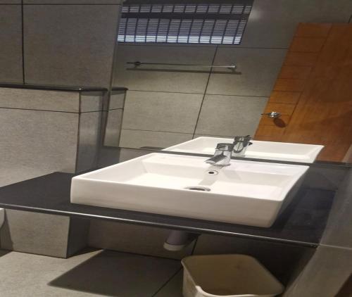 a bathroom with a white sink and a mirror at Hotel Glanton Manor in Ooty