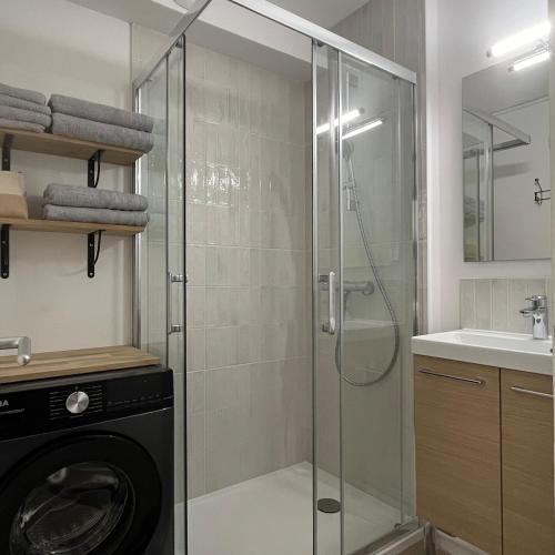La salle de bains est pourvue d'une douche en verre et d'un lave-linge. dans l'établissement T2 au calme à 200m de la plage avec parking privé, à Sète