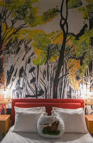 a bedroom with a painting of trees on the wall at Beit Tamanna Guesthouse in Beirut