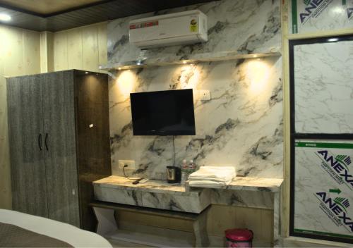a bathroom with a tv on a marble wall at Ganga Riverfront Rooms And Banquet in Prayagraj