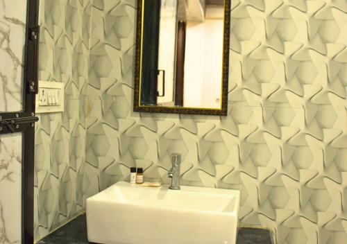 a bathroom with a white sink and a mirror at Ganga Riverfront Rooms And Banquet in Prayagraj