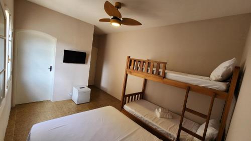 a bedroom with two bunk beds and a ceiling fan at Pousada Flor de Lótus Caraguá in Caraguatatuba