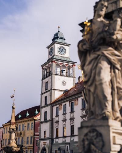 a building with a clock tower with a statue in front of it at Elzet penzion in Třeboň