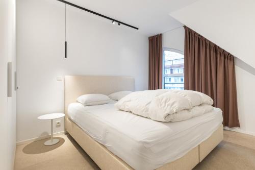 Un dormitorio con una cama con sábanas blancas y una ventana. en Villa Normandie 22 Gar, en Knokke