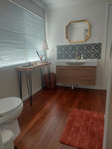 a bathroom with a toilet and a sink and a mirror at Edenvale Homestead in Taabinga