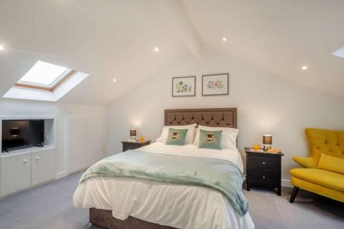 Un dormitorio con una cama y una silla amarilla. en Annedd Lon, en Abersoch