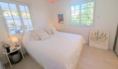 - une chambre avec un grand lit blanc et 2 fenêtres dans l'établissement Ref MAURESQUE by Palmes d Or Properties, au Golfe-Juan