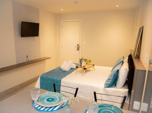 a bedroom with a bed and a table with plates on it at Apart-hotel Cantinho da Serra in Nova Friburgo