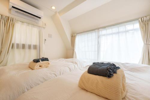 a bedroom with two white beds and a window at 楽逸グループ 池袋瑞月苑3F 111Tc in Tokyo