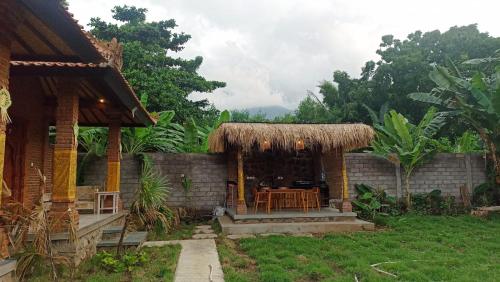 une maison avec une table et un toit de paille dans l'établissement De Sudi Bungalows, à Pemuteran
