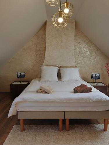 a bedroom with a bed with white sheets and a chandelier at Chez Simone - Charming cottage - Ideal for 6 people in Saint-Valery-sur-Somme