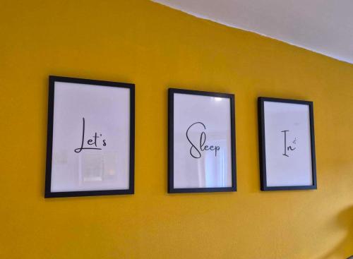 three pictures on a yellow wall with writing on them at Sied Yr Ardd in Ystradgynlais
